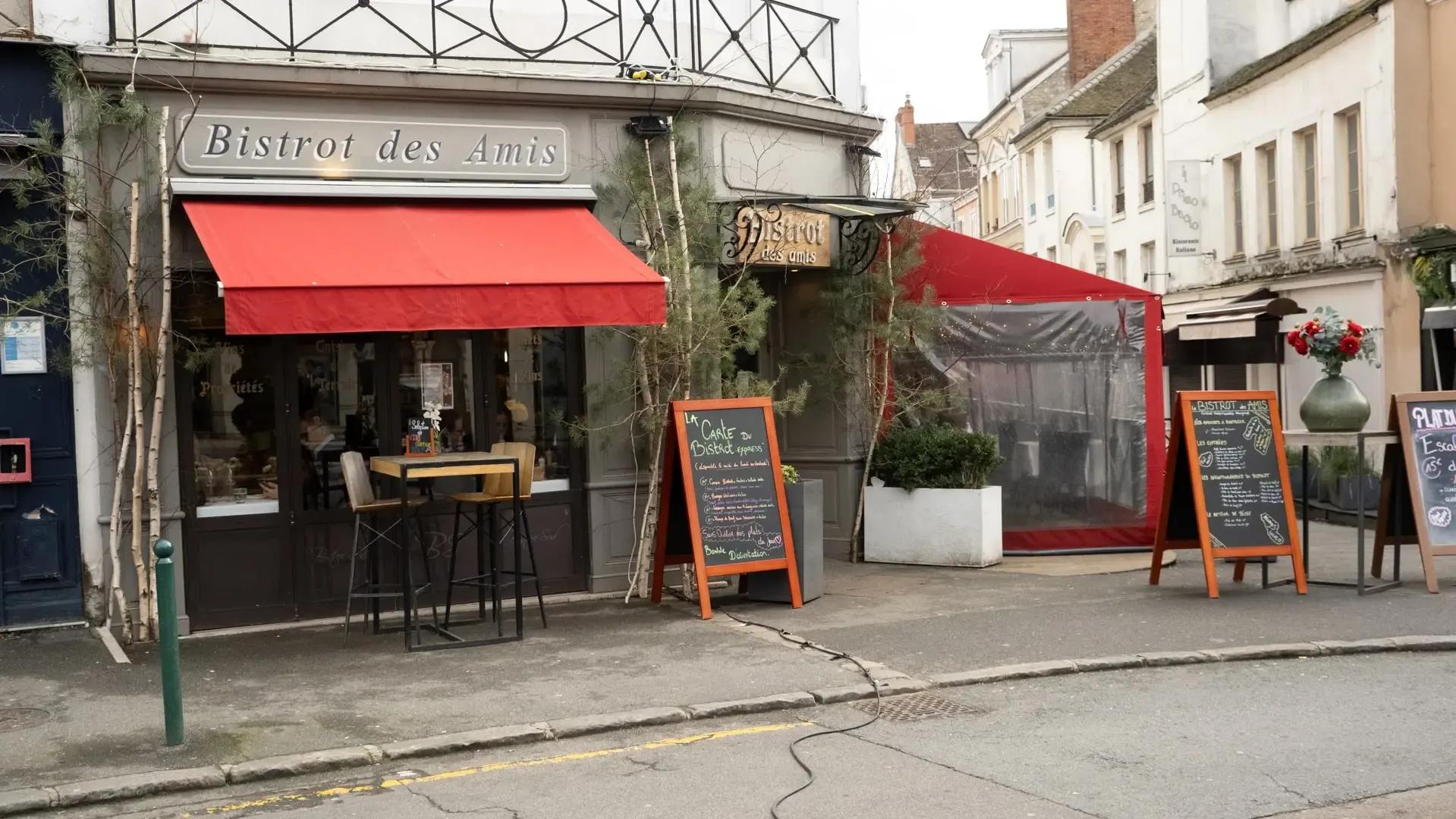 La façade du Bistrot des Amis et sa terrasse sous l’auvent rouge