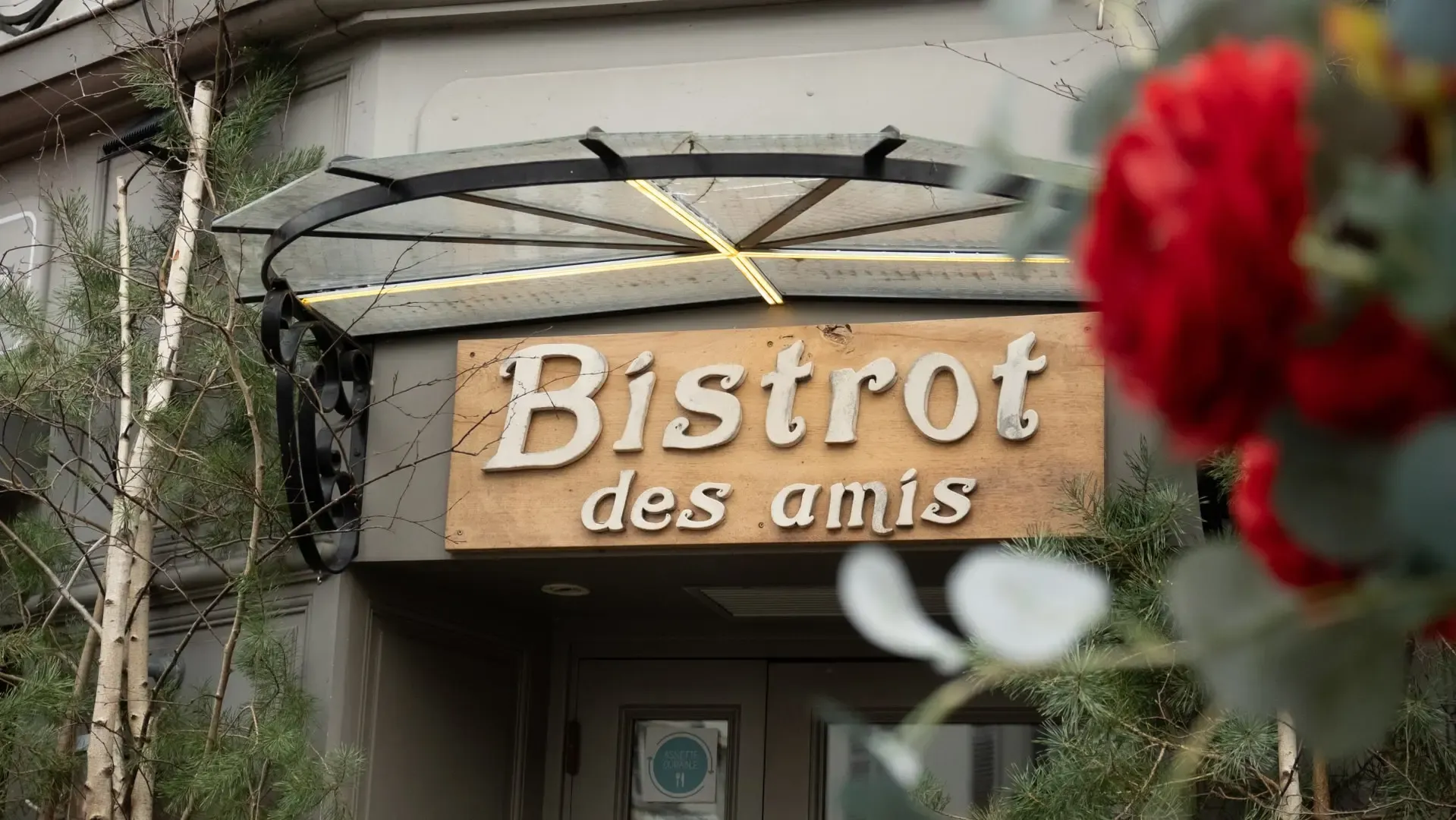 L’enseigne en bois du Bistrot des Amis, entourée de fleurs