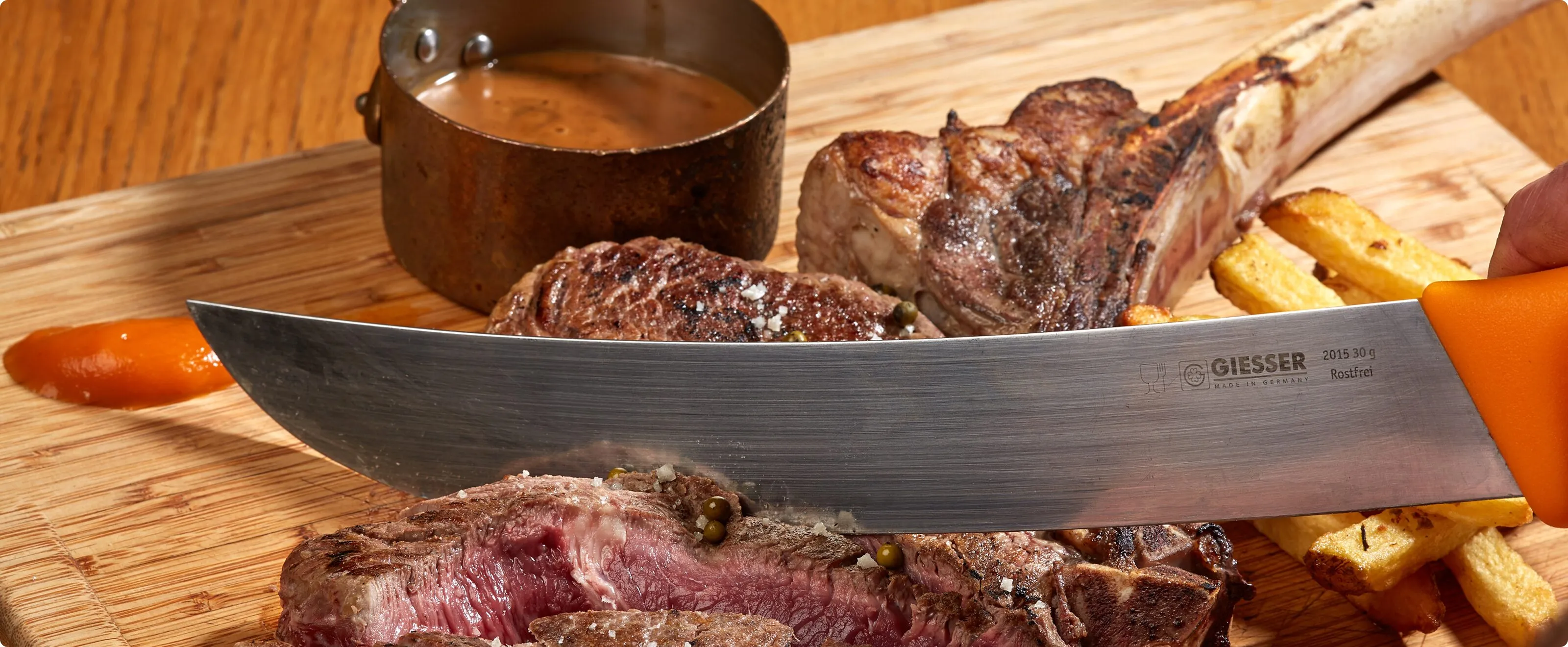 Côte de bœuf tranchée au couteau sur une planche en bois, avec sa sauce en casserole de cuivre et ses pommes de terre